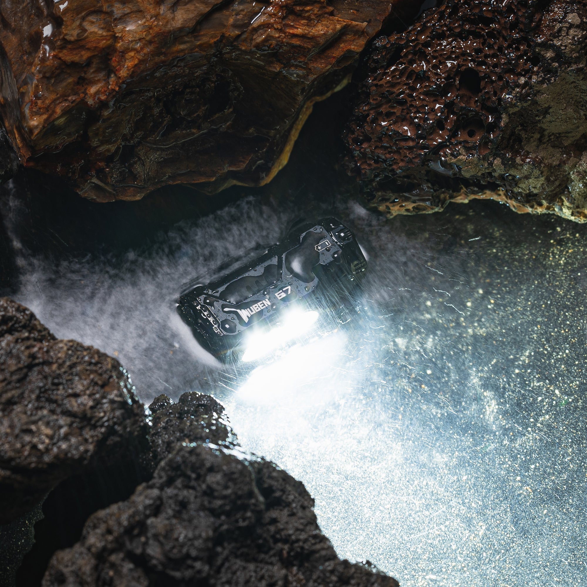 WUBEN E7 LED Lommelygte belyst i vandet mellem klipper, viser dens robuste design og kraftige lysstyrke